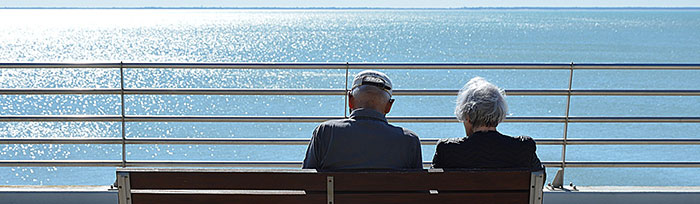 Photo of Elderly Couple on a bench looking at the water